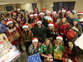 St. Clair College's gerontology students, Hotel-Dieu Grace Healthcare team, COAST Team, Assisted Living Southwestern Ontario volunteers, and Home Instead caregivers are shown during a wrapping party for Christmas gifts to be distributed to isolated seniors through the Be a Santa to a Senior program.