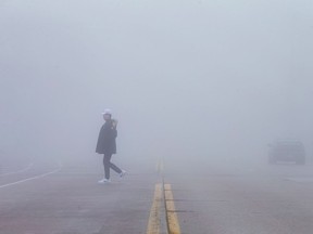 A man crosses University Avenue, under a blanket of fog Sunday, Jan. 22, 2017.