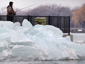 An angler fishes under the Ambassador Bridge on Tuesday, Jan. 17, 2017 near a pile up of ice.