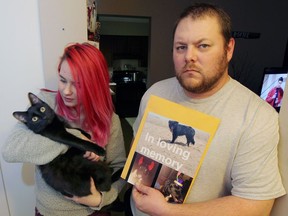 Kevin Laporte, right, is looking for the driver of a vehicle which killed his dog, Kiki, near Wheatley on Tuesday. Laporte's girlfriend's daughter,  Katrina Scurr, left, holds the pet cat, Midnight, on Jan. 5, 2016. The animal-loving family are devastated about the loss of Kiki, shown in photos held by Laporte.