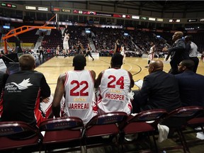 Windsor Express players watch action from the bench as teammate Nick Evans slam dunks the ball against the Orangeville A's at the WFCU Centre in Windsor on Dec. 30, 2016.