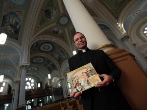 Rev. Patrick Beneteau displays his new book on the murals at St. Joseph's Church in River Canard on Jan. 20, 2017.