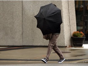A man hangs on tight to his umbrella as he battles the wind while walking along Pelissier Street in Windsor on Oct. 29, 2012.