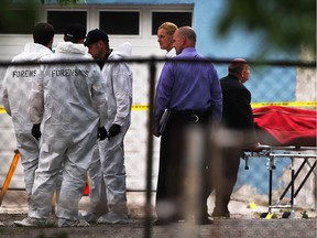 Windsor police forensics team, left, and lead investigators continue their investigation at the rear of a Brant Street building as body removal services, right, takes away the body of a man found dead on June 4, 2015.