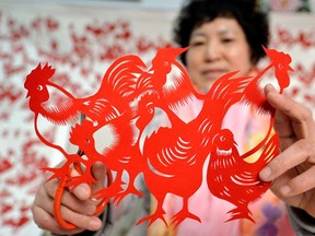 A craftswoman in Handan, China, shows paper-cut roosters on Jan. 16, 2017.