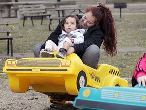 Kelsey Holland takes her daughter Adrieonna Dodge-Hollard, 2, for a spin on a playground ride on Matchett Road near Malden Park February 22, 2017.  Windsor broke another, long-standing temperature record, soaring to 16C.