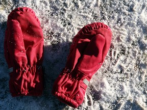 Red winter gloves are pictured in the snow.