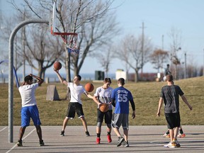 A group of teens in shorts and T-shirts plays basketball at the Belle River Marina on Feb. 18, 2017.