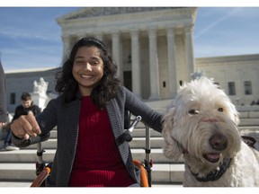 In this Oct. 31, 2016 file photo, Ehlena Fry of Michigan, sits with her service dog Wonder, while speaking to reporters outside the Supreme Court in Washington. The Supreme Court says a lower court should take another look at whether Fry, who has cerebral palsy can sue Michigan school officials over their refusal to let her to bring a service dog to class.