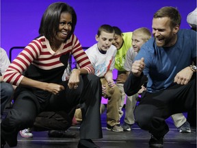 In this Feb. 9, 2012, photo, first lady Michelle Obama and Bob Harper of The Biggest Loser, right in blue shirt, do the Interlude dance during a Let's Move event with children from Iowa schools at the Wells Fargo Arena in Des Moines, Iowa. Harper tells TMZ he suffered a heart attack and was hospitalized for several days in February 2017.