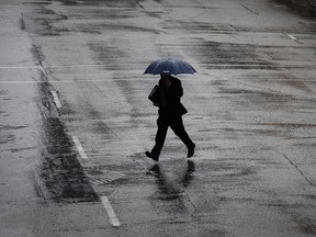 An umbrella covered man crosses Pitt Street in the rain in Windsor on Feb. 7, 2017.
