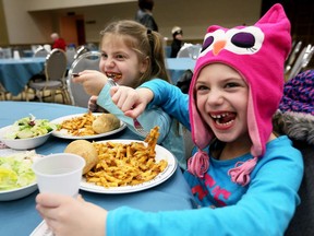 Five-year-old Natalie Brosseau, right, and her seven-year-old sister Leah enjoy pasta and salad at Caboto Club of Windsor during Pasta Night for W.E. Care for Kids and other charities February 1, 2017.