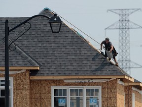 A construction worker shingles the roof of a new home in a development in Ottawa on July 6, 2015.