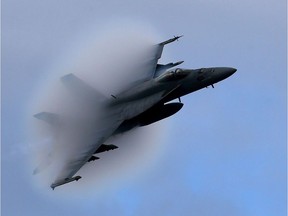 A F-18 Super Hornet creates a vapour cone as it flies at a transonic speed while doing a flyby of the USS Eisenhower in the Atlantic Ocean off the coast of Virginia on Dec. 10, 2015.