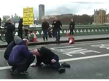 An video grab obtained from the Twitter account of Polish politician and journalist Radosaw Sikorski, shows a man on the ground receiving assistance on Westminster Bridge on March 22, 2017 in London. British police shot a suspected attacker outside the Houses of Parliament in London after an officer was stabbed in what police said was a "terrorist" incident. The building in the heart of the British capital was immediately sealed off and MPs and staff ordered to remain inside. TV pictures showed traffic halted on the nearby Westminster Bridge and emergency vehicles swarming around. The busy bridge was completely shut off to traffic.