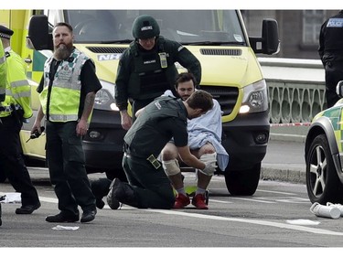 Emergency services staff provide medical attention to injured people close to the Houses of Parliament in London, March 22, 2017.