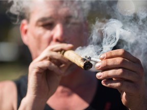 A man smokes some marijuana as others gather to celebrate National Marijuana Day on Parliament Hill in Ottawa on April 20, 2016.
