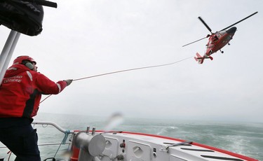 Leading Seaman Jeff Faucher, a crew member of the Canadian Coast Guard rescue boat Cape Dundas, is shown during a rescue exercise on May 17, 2016 with a helicopter from the United States Coast Guard.