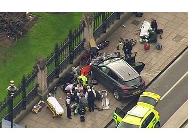 In this image taken from video police officers gather around a car adjacent to Houses of Parliament in London, March 23, 2017 after the House of Commons sitting was suspended as witnesses reported sounds like gunfire outside. The leader of Britain's House of Commons says a man has been shot by police at Parliament.