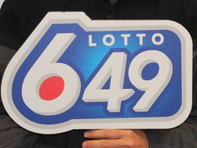 A winner holds up a Lotto 6/49 sign.