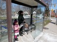 Mbuyi Mireille and her daughter, Eunice Meta Mbaya, 4, patiently wait for Transit Windsor in a bus shelter on Wyandotte Street East and Jefferson Boulevard on March 16, 2017.  Hard to see at first, nasty graffiti has been written in black marker on the glass of the shelter.  The graffiti mentions Prime Minister Justin Trudeau and immigrants. A portion of this image has been distorted due to content.