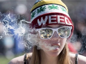 A woman exhales while smoking a joint during the annual 420 marijuana rally on Parliament hill on April 20, 2016 in Ottawa.