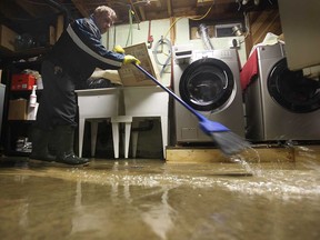 A homeowner on Wachna Drive in Windsor's east end attempts to clear water from his flooded basement after heavy rainfall in May 2011.