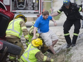 Lakeshore firefighters and a paramedic help a man after he was pulled from a pickup truck that slid into the ditch on Lakeshore Rd. 113, Monday, April 10,  2017.  The male was taken to hospital with minor injuries.