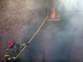 A firefighter douses a blaze at a home on Wales Court in LaSalle on April 23, 2017.