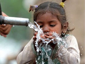 A young Pakistani girl drinks from a hand pump in Lahore on March 27, 2014.