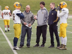 Windsor Lancer football coaches Austin Kennedy, left, Jordan Brescasin (grey) and Evan Pszczonak, right, speak with players Cody Knights, left, and Daynar Facey, right, during spring practice at Alumni Field on April 4, 2017.