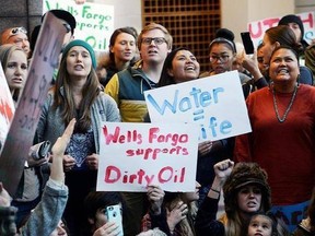 FILE - In this Oct. 31, 2016, file photo, protesters hold a rally in the lobby of the Wells Fargo Center building in Salt Lake City in support of the Standing Rock Sioux against the Dakota Access pipeline. Opposition to the four-state Dakota Access oil pipeline has boosted efforts to persuade banks to stop supporting projects that might harm the environment or tread on indigenous rights. (Al Hartmann/The Salt Lake Tribune via AP, File)