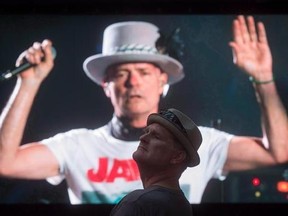 Lead singer Gord Downie is seen performing on a screen as a man watches during a viewing party for the final stop in Kingston, Ont., of a 10-city national concert tour by The Tragically Hip, in Vancouver, B.C., on Saturday, August 20, 2016. THE CANADIAN PRESS/Darryl Dyck