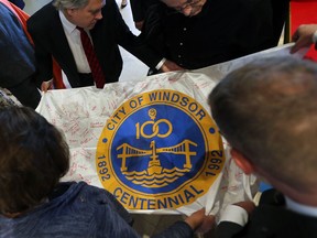 A time capsule that was put together for Windsor's centennial anniversary in 1992 was opened 25 years later on May 16, 2017. The large W-shaped container held 100 items varying from newspaper clippings, sports items and photos. People check out a city flag that was in the time capsule with many signatures.