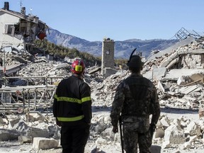 A firefighter and soldier look over rubble in the hilltop town of Amatrice in central Italy, Oct. 30, 2016, following one of the aftershocks to the  powerful earthquake that hit the same area in August. Thousands were left homeless.