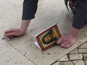 A worshipper walks on her knees as she holds a rosary and a book with the image of Jesus Christ in the Sanctuary of Fatima on May 11, 2017 in Fatima, Portugal.