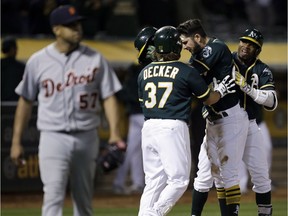 Oakland Athletics' Matt Joyce, second from right, celebrates with Jaff Decker (37) and Rajai Davis, right, after scoring the winning run against the Detroit Tigers in the ninth inning on Saturday, May 6, 2017, in Oakland, Calif.