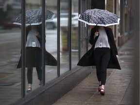 A woman is reflected in the window of the Starbucks in downtown Windsor as she takes cover from the rain under her umbrella on May 4, 2017.
