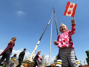 Lily Chabot waves a flag while workers construct the Great Canadian Flag at Dieppe Gardens in downtown Windsor, Ontario on May 12, 2017.