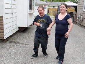 Windsor, Ontario. June 6, 2017.  Heather Michaluck, 22, holds the hand of her younger brother Adam at their home on Partington Avenue.  Heather, who is developmentally challenged, is a recent graduate of Work Matters.  The Work Matters program has taught Heather many self-reliant activities, like how to take public transit. (NICK BRANCACCIO/Windsor Star)