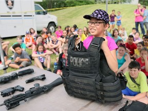 Marissa Dodich, 11, of L.A. Desmarais Public School, tries to lift a police vest with imbedded ballistic plates as part of the VIP (Values, Influence, Peers) demonstration day at Major F.A. Tilston Armoury and Police Training Centre on June 13, 2017.