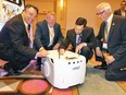 Hon. Brad Duguid, centre right, Minister of Economic Development and Growth signs his name on top of an Autonomous Intelligent Vehicle (AIV) to the delight of Omron executives Frank Pennimede, left, and Michael Joy and newly elected APMA president Roy Verstraete, right, at Automotive Parts Manufacturers' Association annual conference at Caesars Windsor on June 14, 2017.