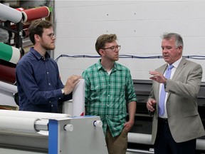 Ontario Labour Minister  Kevin Flynn, right, speaks with Chris Oliver, left, and Matt Oliver of Oliver Signs at their Oldcastle company on June 15, 2017.