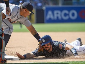 Austin Hedges of the San Diego Padres is tagged out by Miguel Cabrera of the Detroit Tigers as he tries to get back to first base during the fifth inning of a baseball game at PETCO Park on June 25, 2017 in San Diego, California.