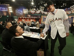 Trevor Rogers, a pitcher from Carlsbad High School in Carlsbad, N.M., right, shakes hands with former New York Yankees player Nick Swisher after being selected No. 13 by the Miami Marlins in the first round of the Major League Baseball draft, Monday, June 12, 2017, in Secaucus, N.J.