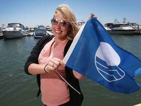 Jessica Deschamps, lead harbour attendant at Colchester Harbour Marina, holds a smaller version of the official Blue Blag that was raised Wednesday as pary of the marina world renowned eco-certification.