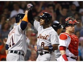 Christian Vazquez of the Boston Red Sox looks on as Justin Upton high fives Victor Martinez of the Detroit Tigers after hitting a grand slam in the fifth inning of a game at Fenway Park on June 11, 2017 in Boston, Massachusetts.