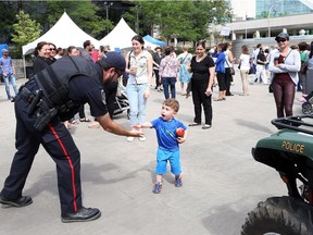 Amherstburg Const. Steve Owen shakes hands with a young attendee at the Emergency Services Introduction to New Canadians display at Charles Clark Square in Windsor on June 15, 2017.