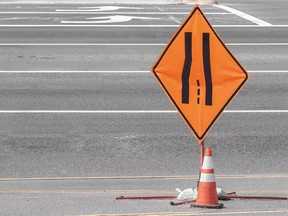 Orange and black traffic lanes merging sign and warning cone. Zipper merging.