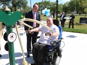 Huron Lodge residents' council vice-president  Osker Rauscher works out as Windsor Mayor Drew Dilkens looks on after the grand opening of a new outdoor accessible workout facility.